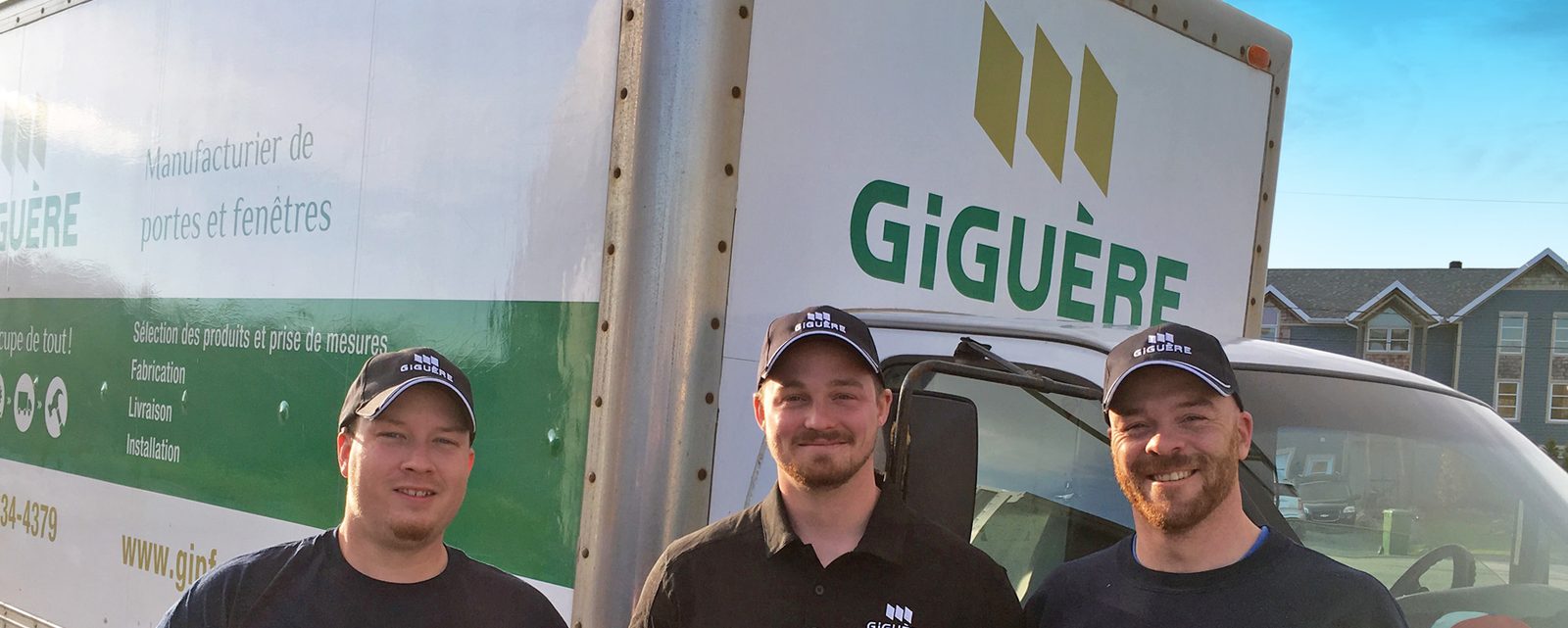 Trois employés en casquette et chandail Giguère devant le camion de livraison au logo vert